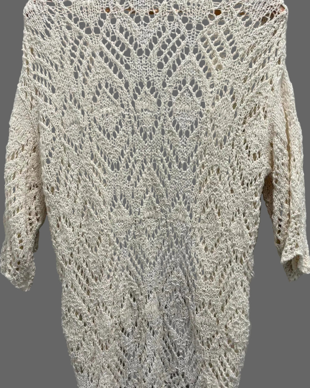 Knitted sweater with a crocheted pattern on a gray background