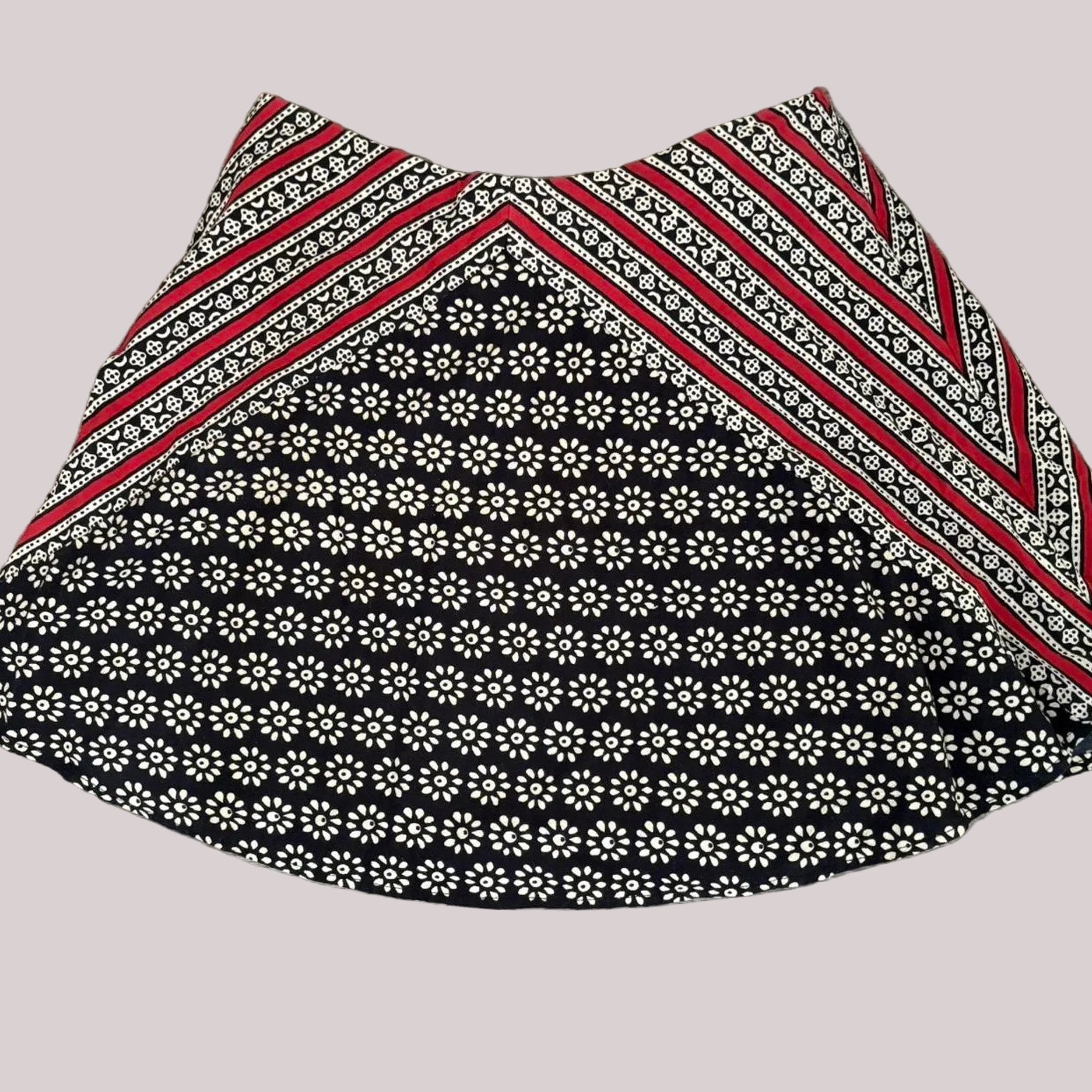 Fabric mini skirt with black and white floral pattern and red stripes on a plain background.