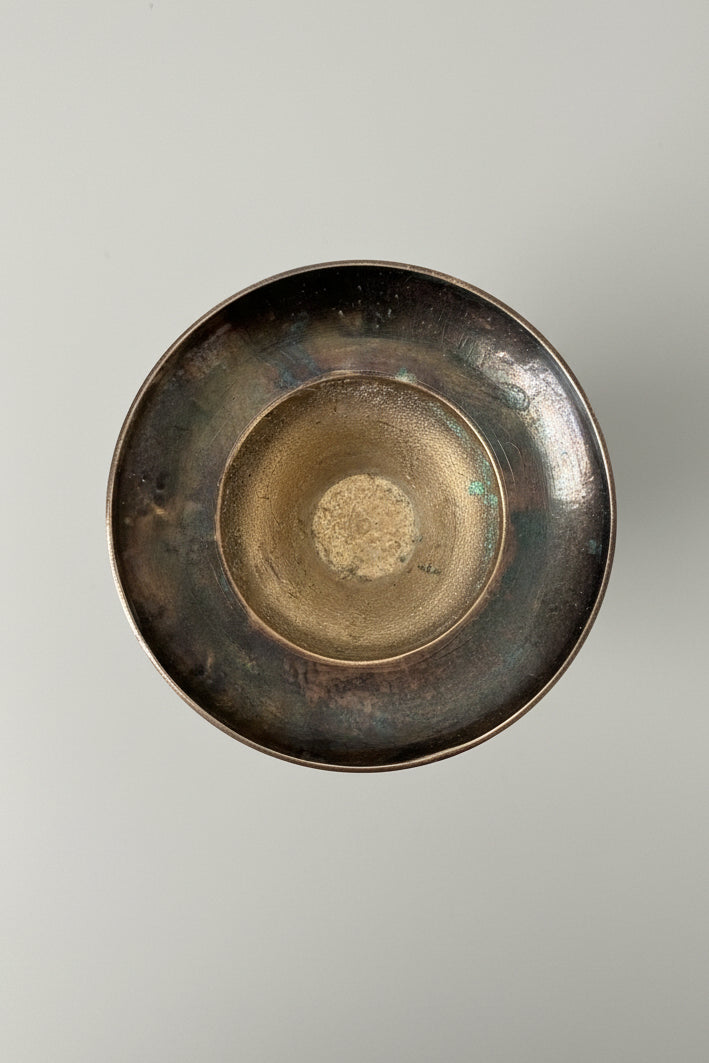 Bottom of a vintage brass patina vase on a gray surface