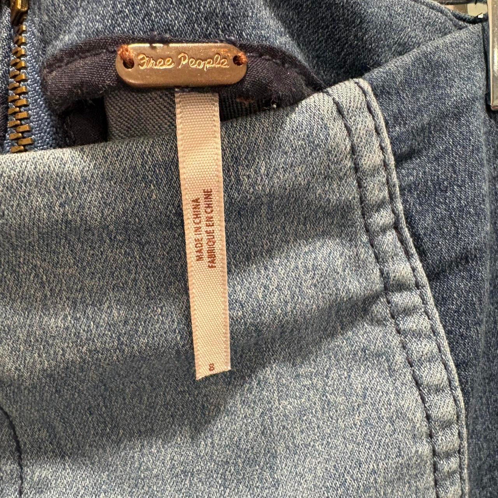 Close-up of a denim label on a denim mini skirt with 'Free People' branding.