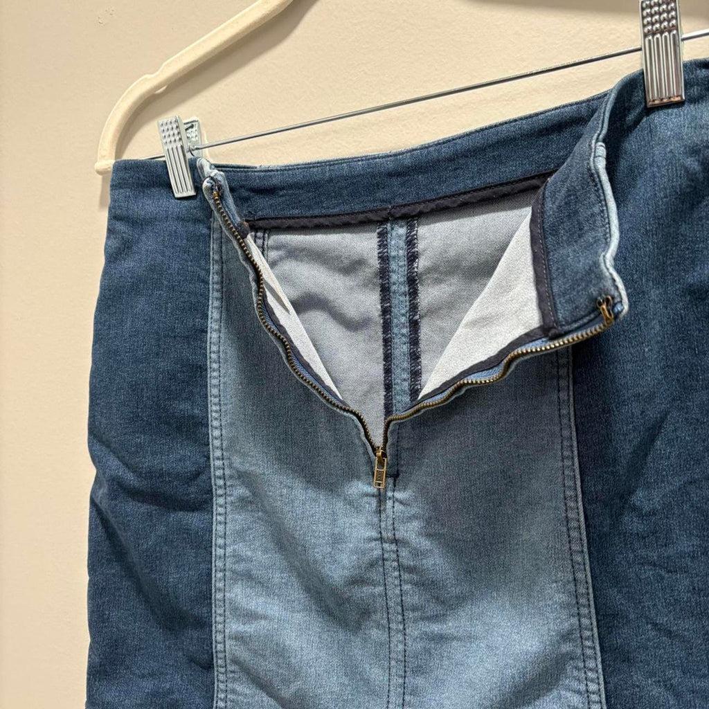 Blue denim mini skirt with an open zipper on a beige background