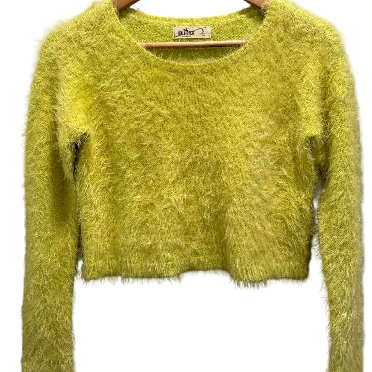 Green fuzzy sweater on a hanger against a white background