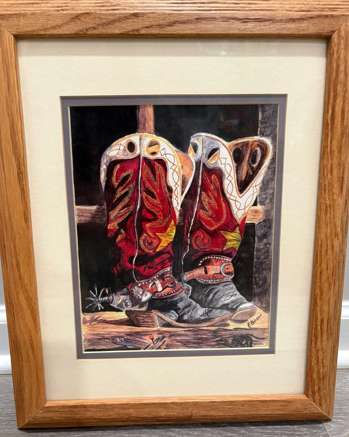 Framed artwork of a pair of cowboy boots with a vintage wooden frame.