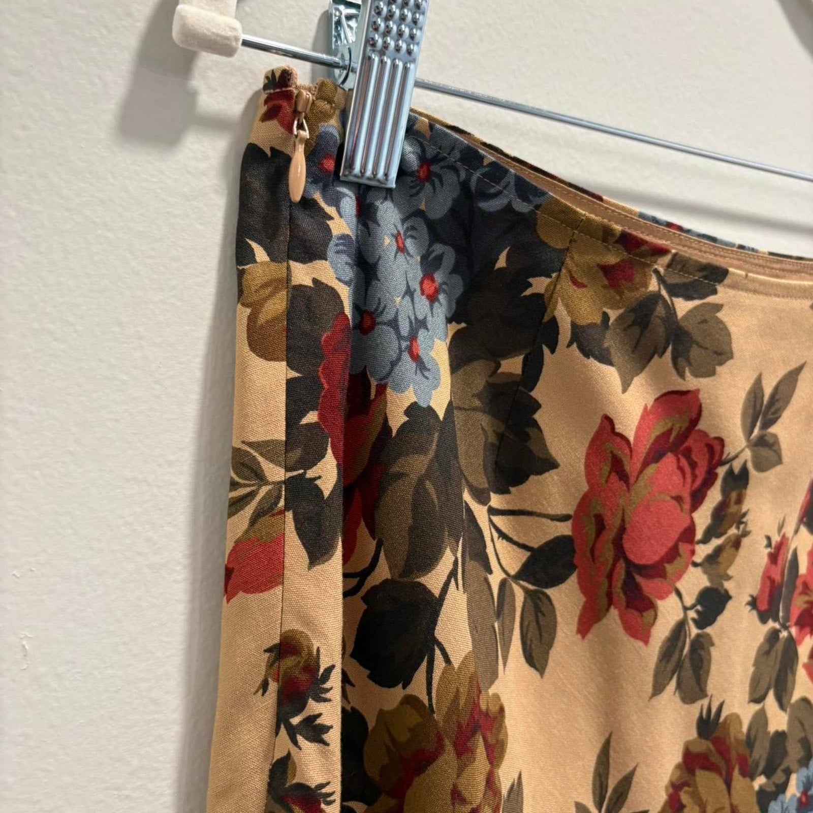 Floral-patterned skirt, showing a side zipper, on a hanger against a white background