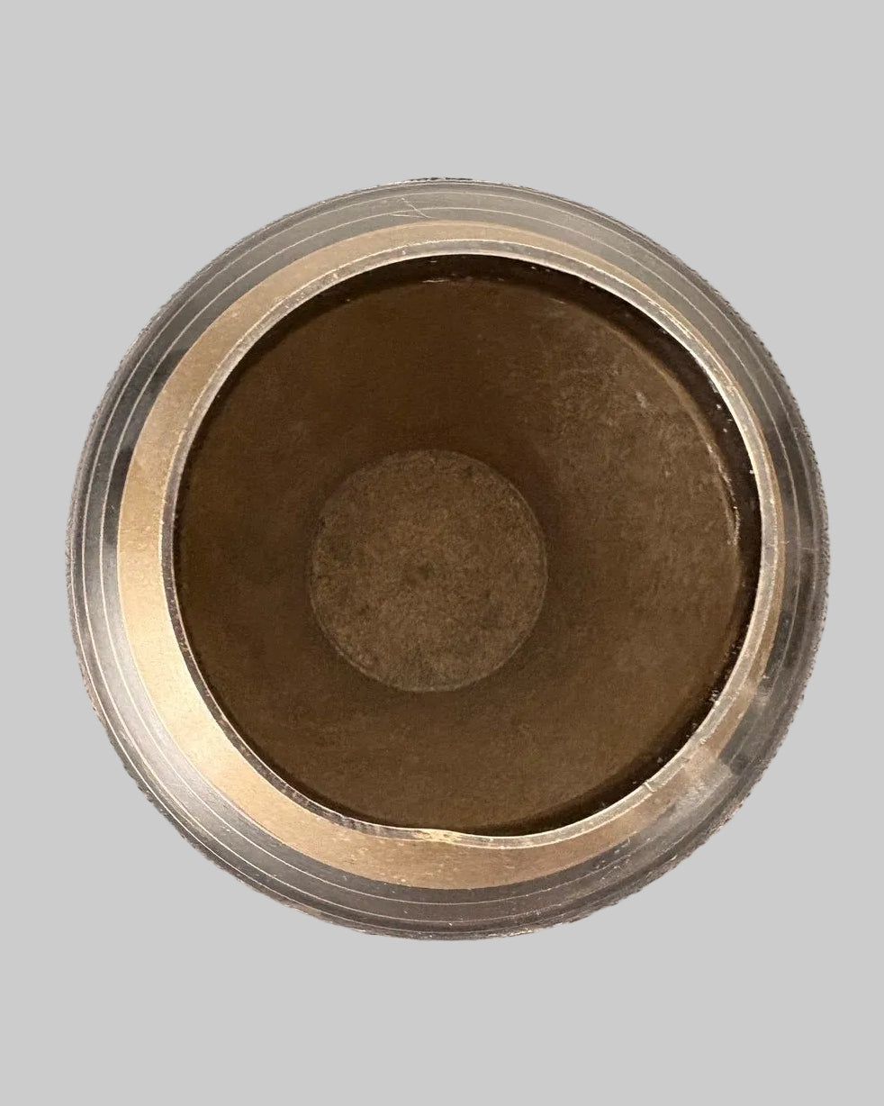 Close-up of inside a vintage brass vase with light patina, and gold detailing on a grey background