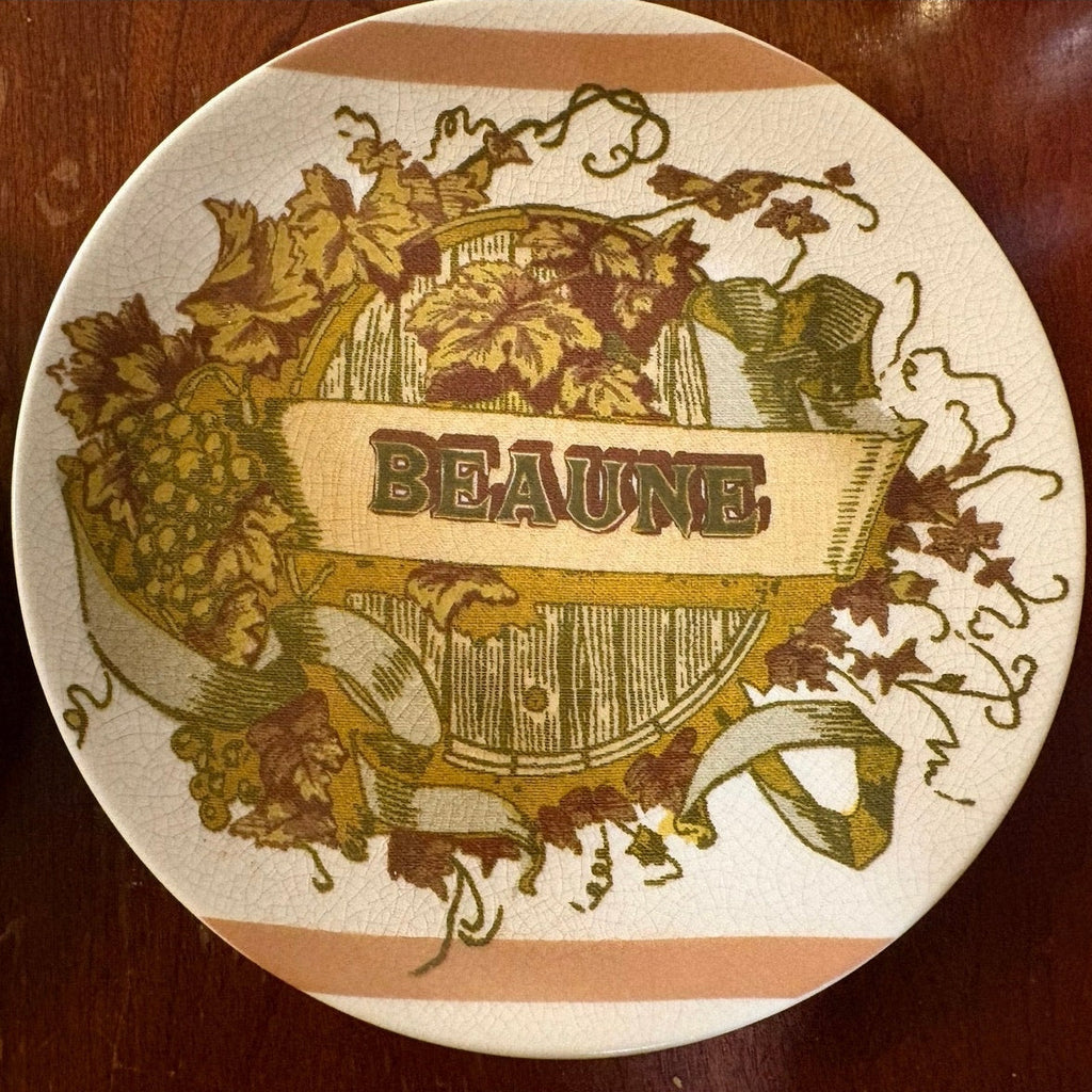 Decorative Pottery Barn plate with 'Beaune' text and vineyard design on a wooden surface