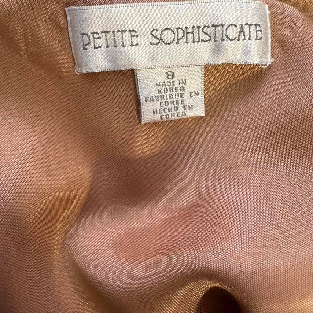 Close-up of a label on a brown fabric with 'Petite Sophisticate' branding.