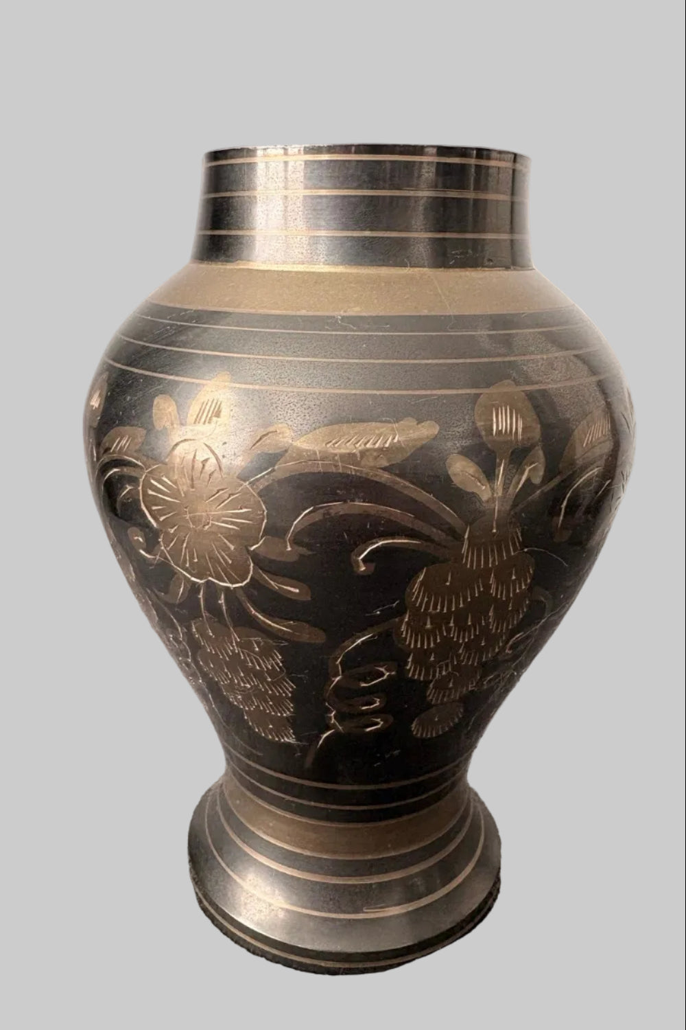 Decorative vintage brass vase etched with floral patterns on a grey background