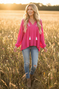 Pink long-sleeve boho top with embroidered decorative elements on a model in a field
