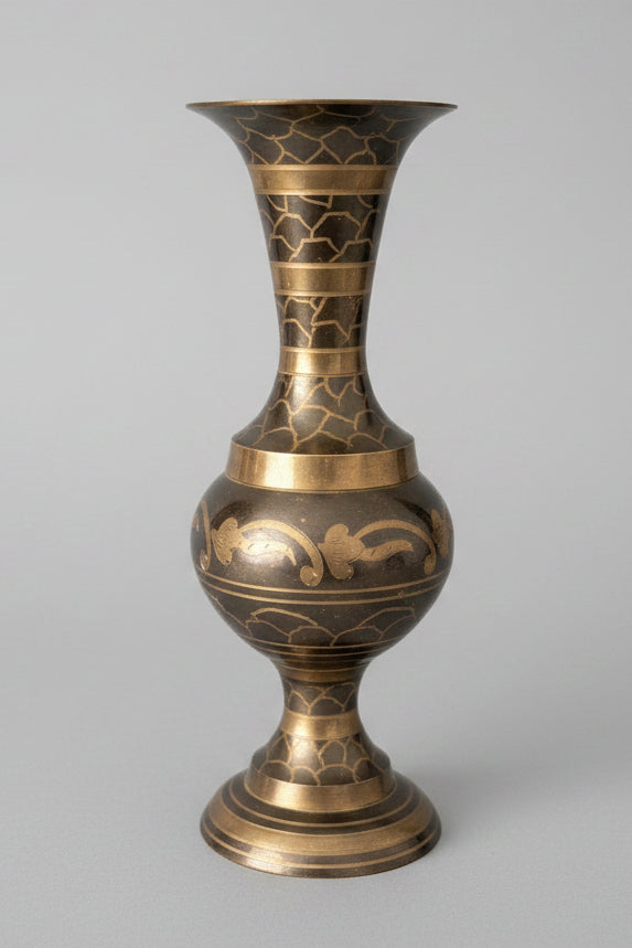 Sunlight hitting a decorative brass vase etched with intricate patterns on a grey surface.