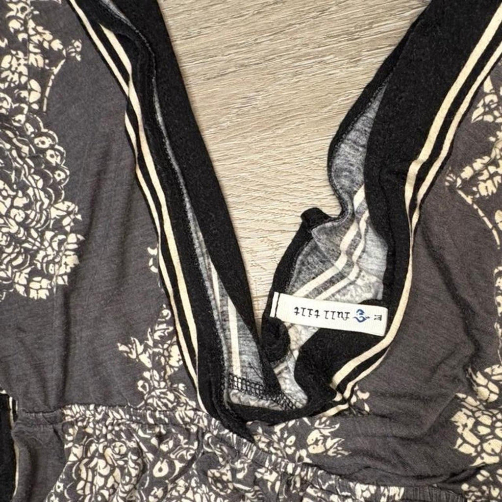 Black and white floral patterned fabric dress with a visible brand label on a wooden surface.