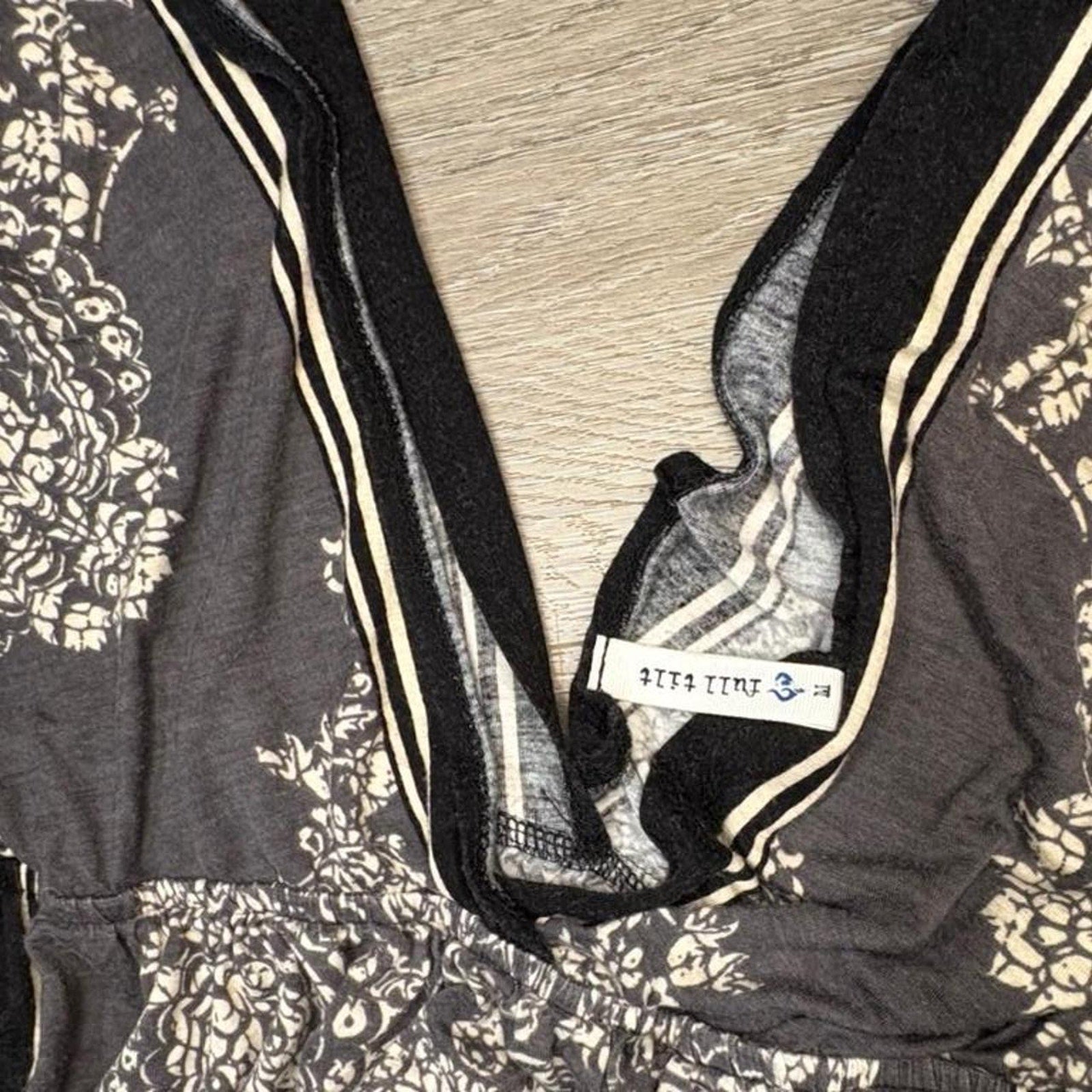 Black and white floral patterned fabric dress with a visible brand label on a wooden surface.