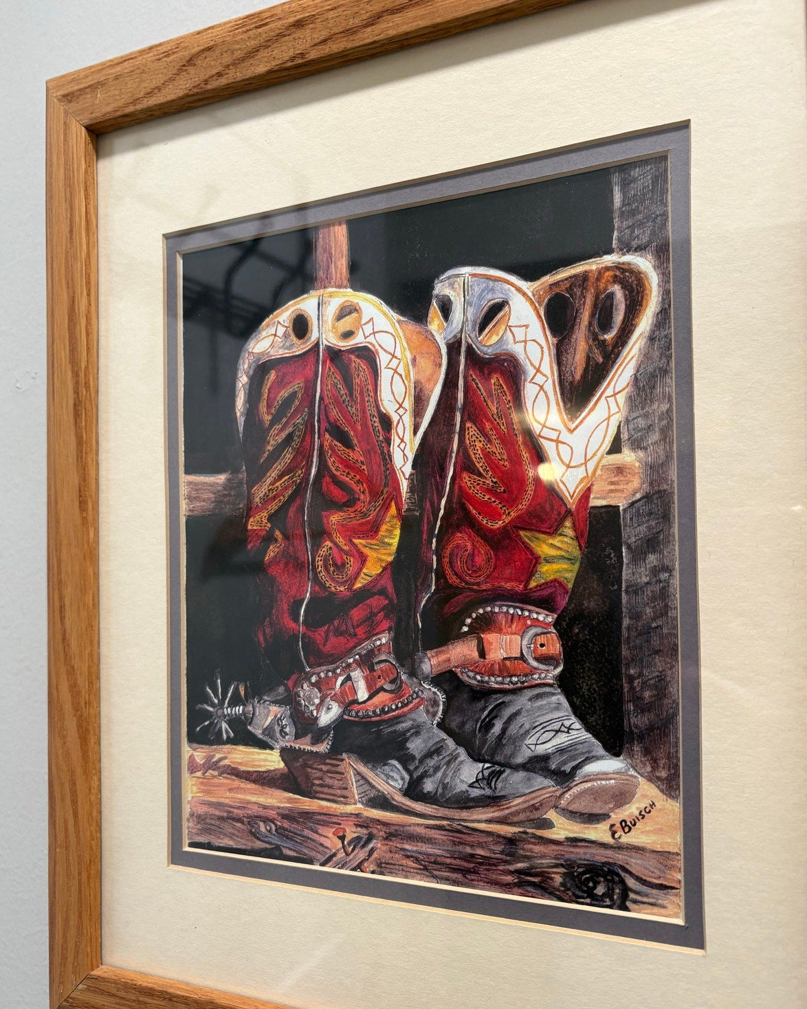 Framed signed artwork of cowboy boots on a wooden surface