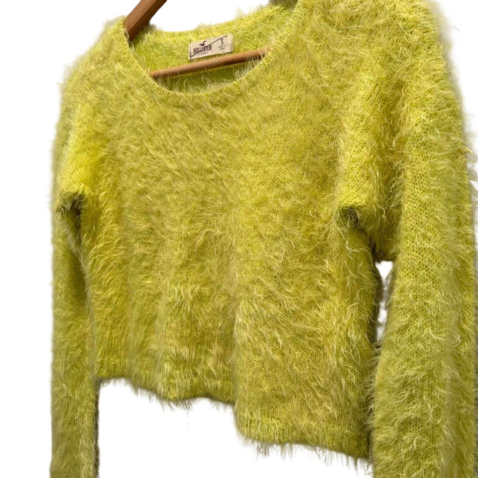 Neon green fuzzy sweater on a hanger against a white background