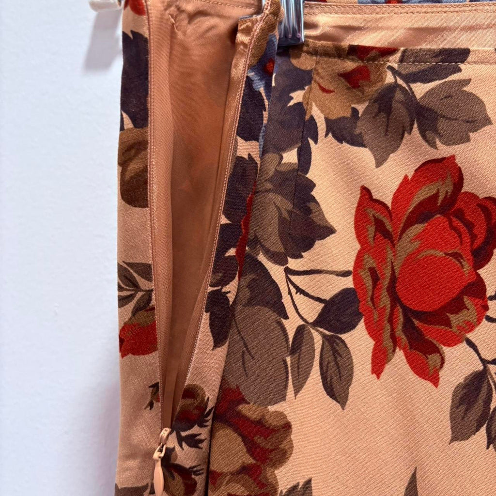 Floral-patterned skirt with an open zipper, and a prominent red flower design on a beige background