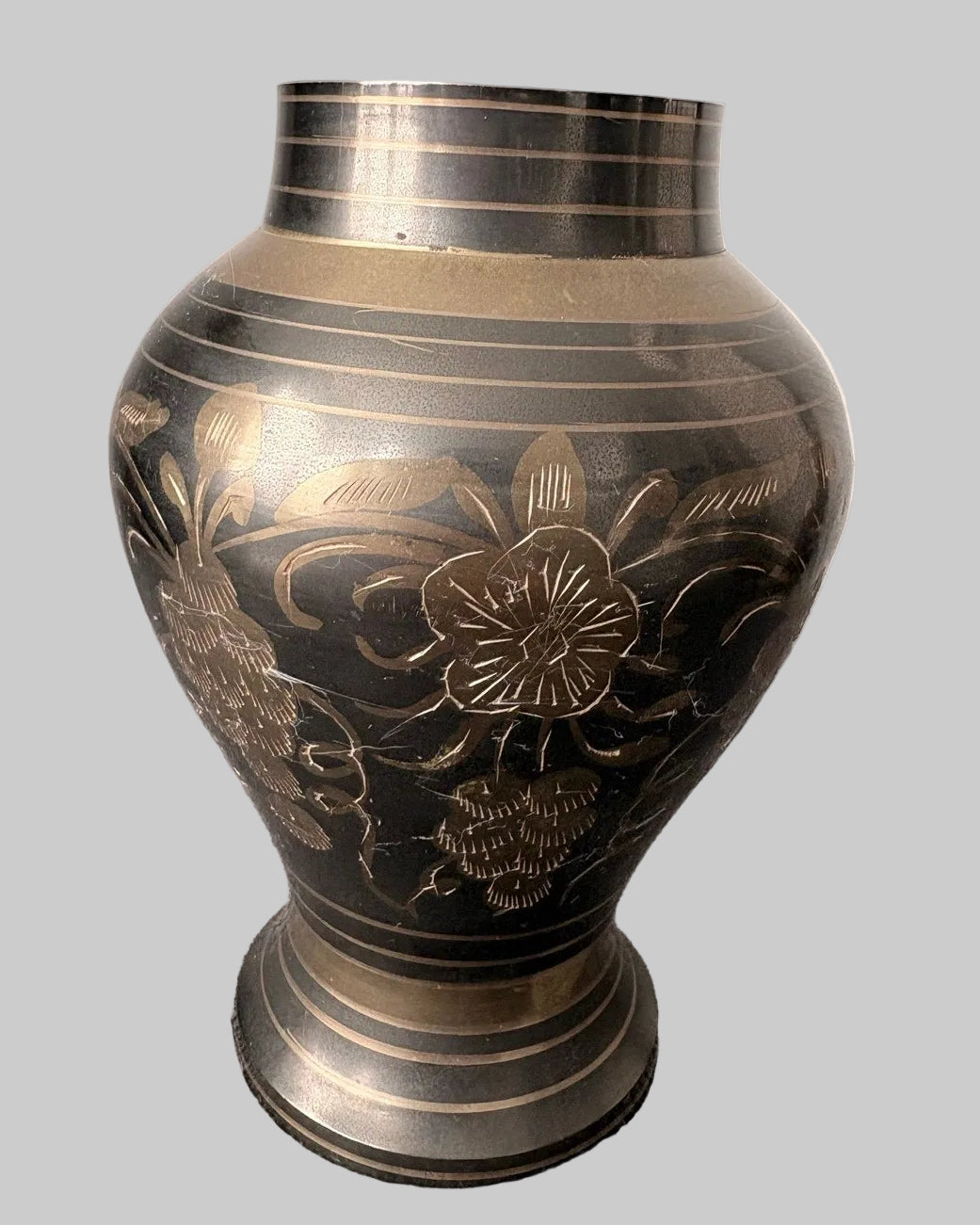 Decorative vintage brass vase etched with floral patterns on a grey background