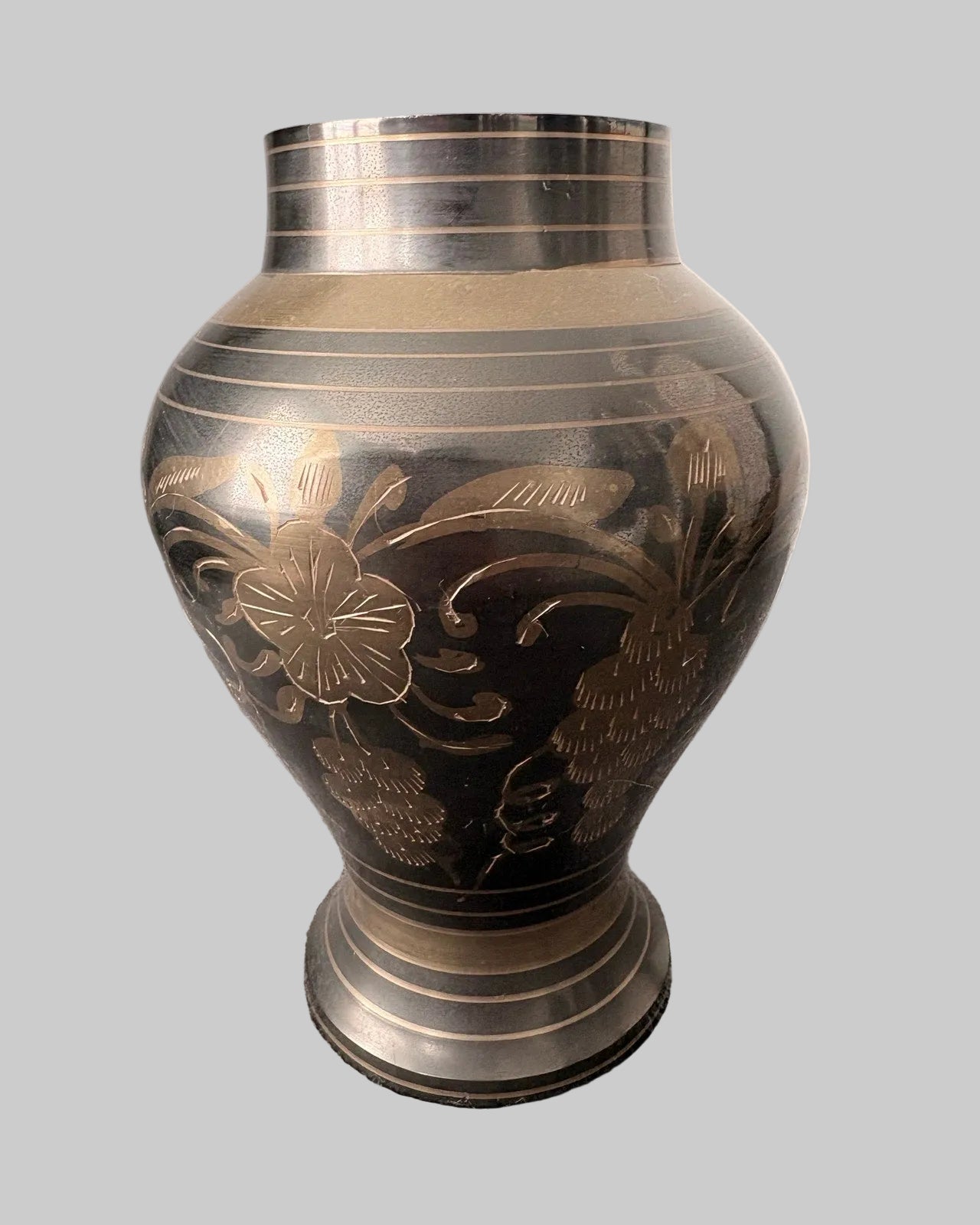 Decorative vintage brass vase etched with floral patterns on a grey background
