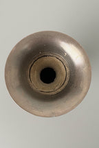Top of brass vase, with patina finish on a grey background