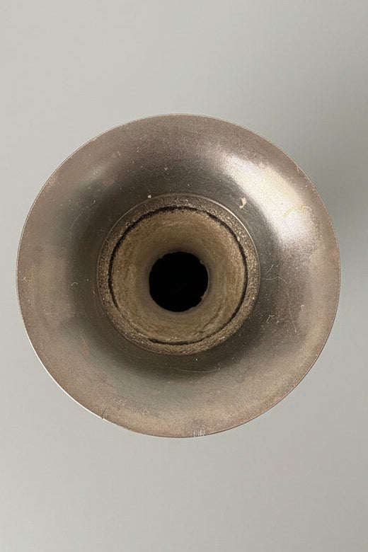 Top of brass vase, with patina finish on a grey background