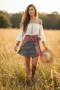 Boho mini skirt with black and white pattern and red and white border on a model in a field