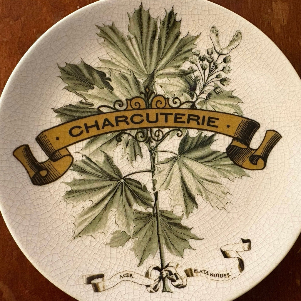 Decorative Pottery Barn plate with leaf design and 'Charcuterie' text on a wooden surface