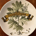 Decorative Pottery Barn plate with leaf design and 'Charcuterie' text on a wooden surface